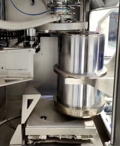 A Volkmann supply cylinder filled with processed metal powder and sealed with a lid is taken over by a mobile transfer module (GTAS / AGV)